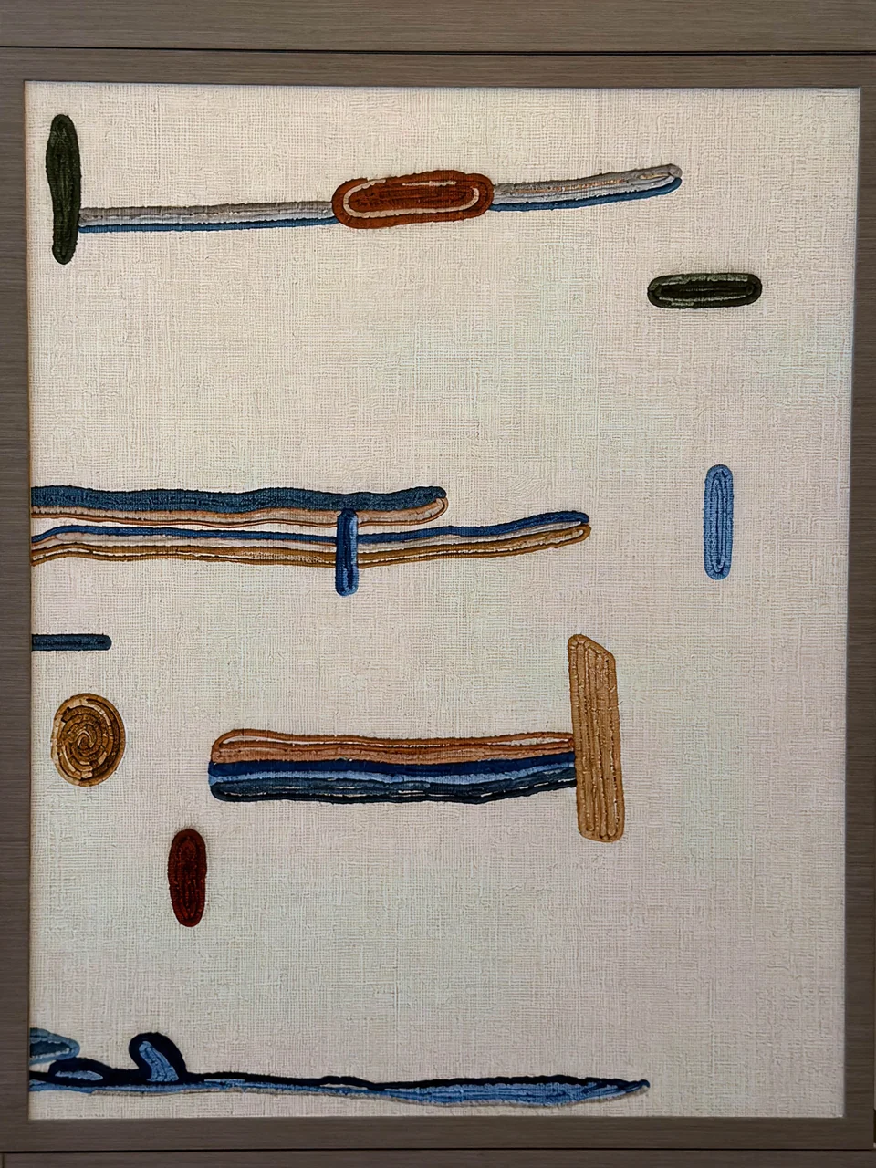 Close view of embroidered blue, rust and green motifs on the textile panel