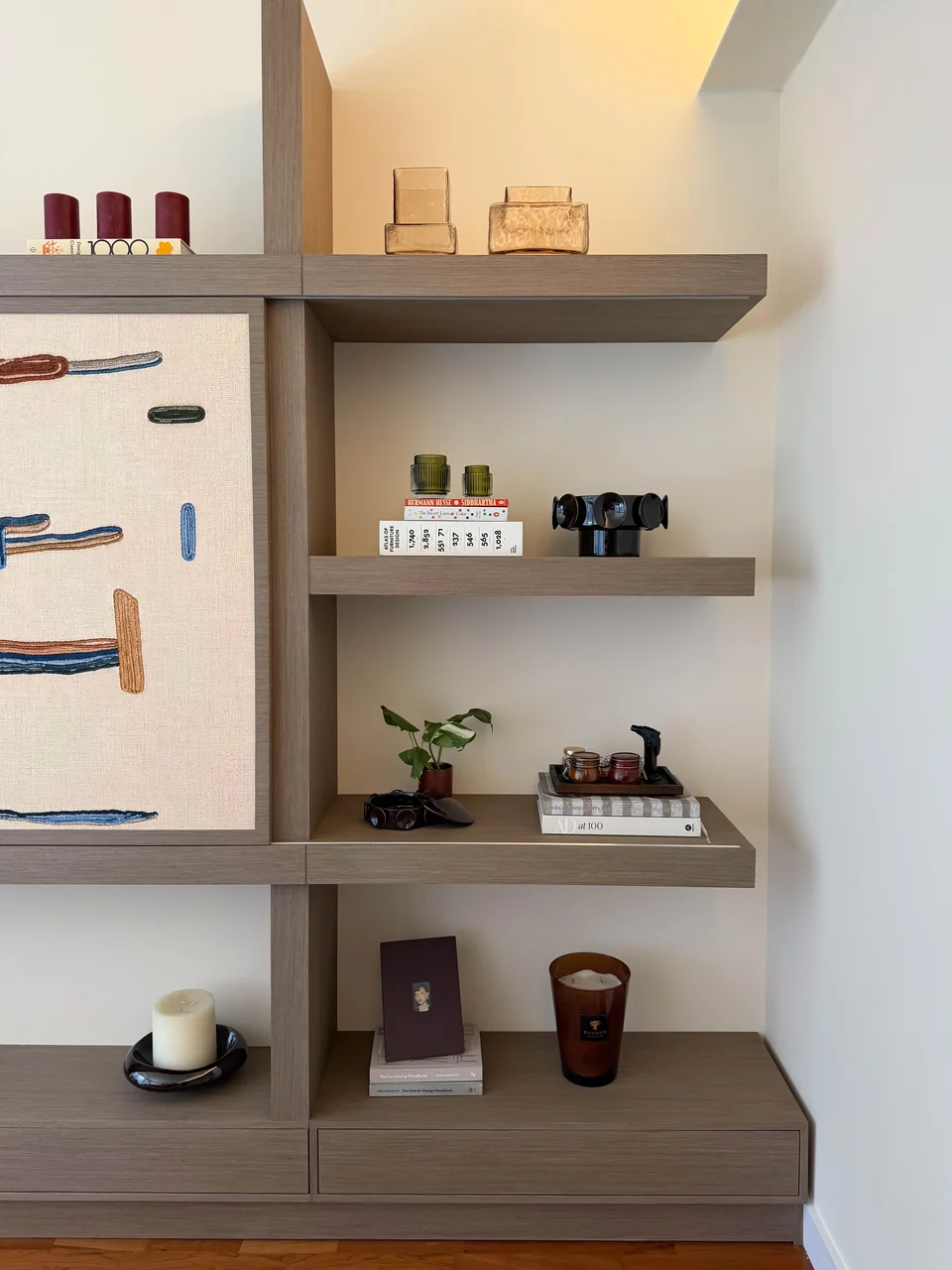Right display shelves and low timber storage beside a patterned panel