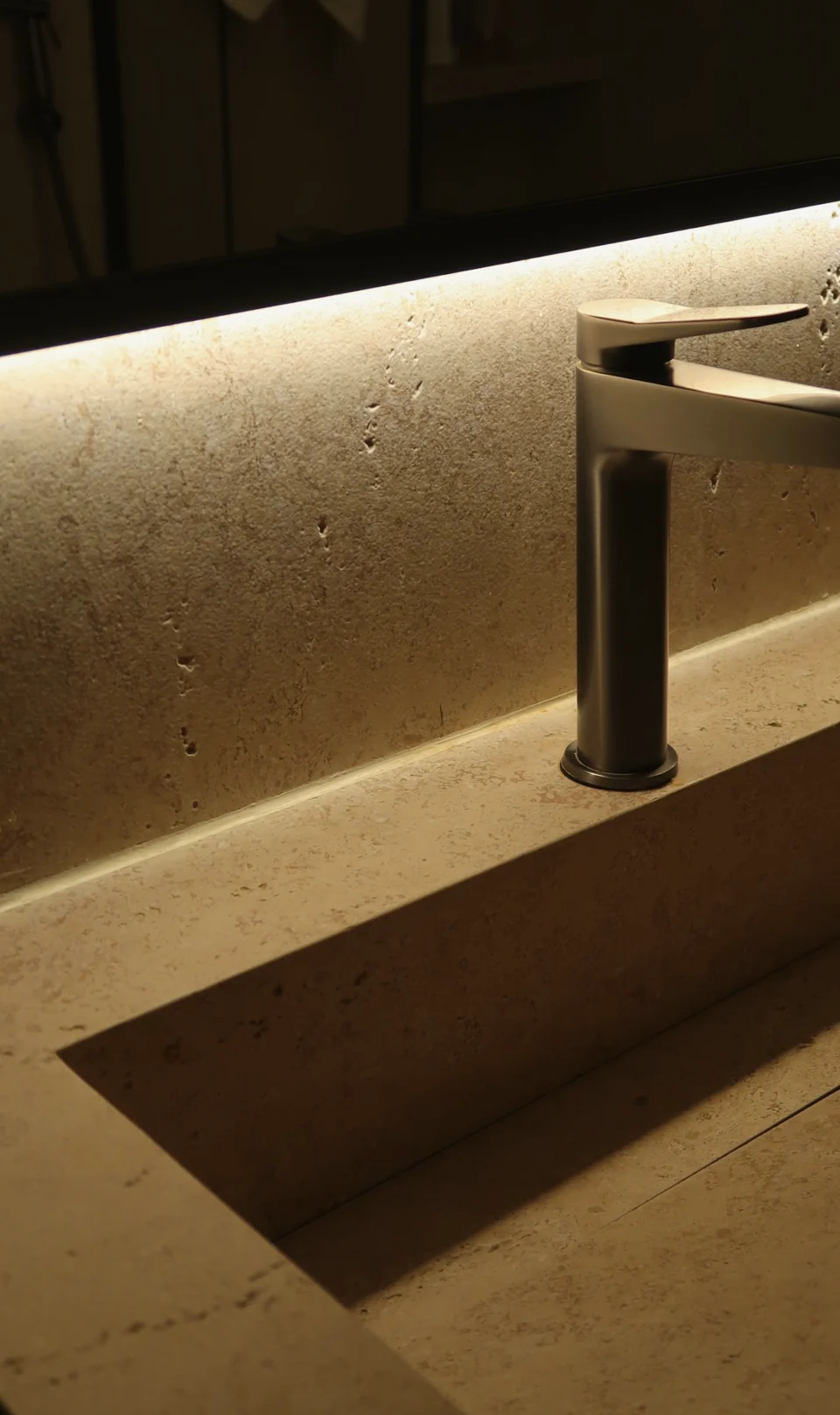 Bathroom vanity detail with integrated basin, dark faucet and concealed lighting in the Mirdif villa