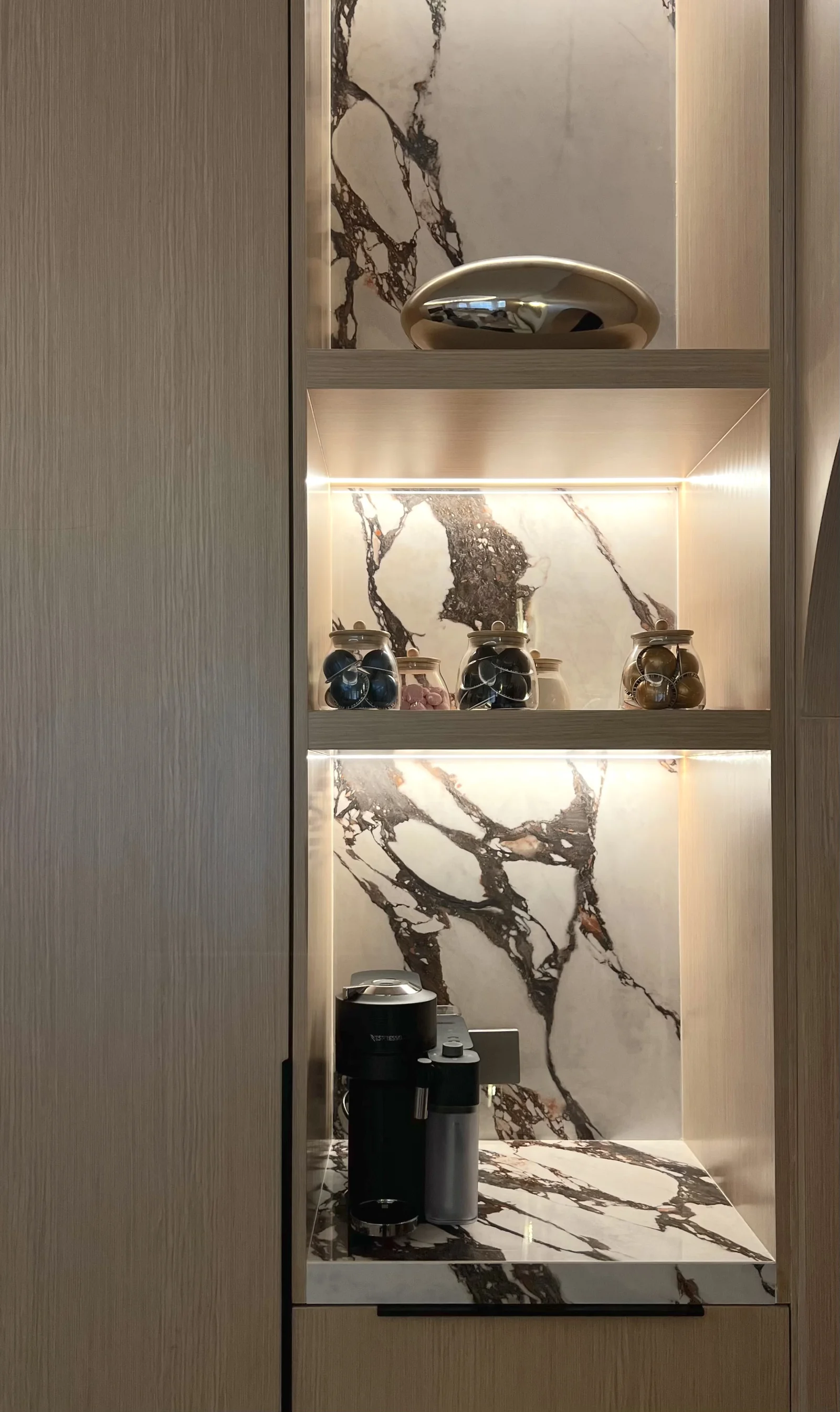 Illuminated marble-backed display shelves and coffee station in the Mirdif villa